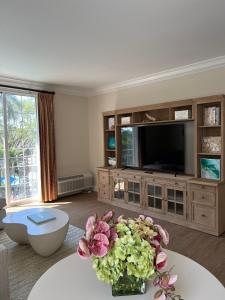 a living room with a tv and flowers on a table at The Capri Inn in Naples