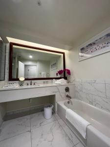 baño blanco con bañera y espejo grande en The Capri Inn en Naples
