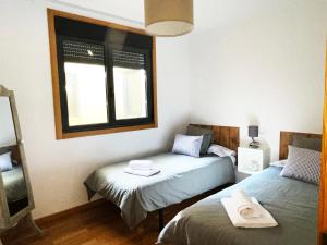 1 dormitorio con 2 camas y ventana en Ático Alquiler Mondaríz Paraiso del agua. Vistas espectaculares, en Mondariz