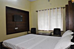 a bedroom with a large white bed and a window at Jhargram Eshani Hotels and Guest House in Jhārgrām