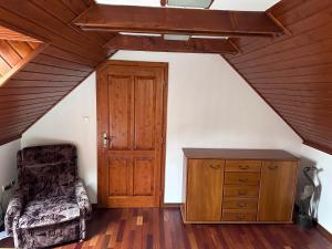 a attic room with a wooden door and a chair at Village Light House in Omšenie