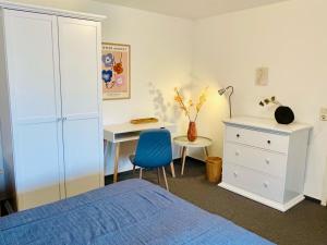 ein Schlafzimmer mit einem Bett und einem Schreibtisch mit einem blauen Stuhl in der Unterkunft Ohl Dörp 10 in Wrixum