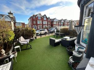 a patio with green grass and chairs on a balcony at North Crest in Blackpool