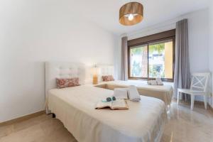 two beds in a white room with a window at CT 199 - Duquesa Village in Manilva