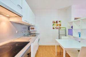 a kitchen with white cabinets and a sink and a table at Precioso Loft en Badalona Centro in Badalona