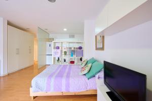バダロナにあるPrecioso Loft en Badalona Centroのベッドと薄型テレビのある寝室