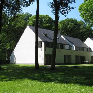 un grande edificio bianco con alberi nell'erba di De Bosdreef - Hengelhoef - duplex met verwarmd openluchtzwembad ad Aan de Wolfsberg