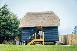 een blauwe hut met een rieten dak en een trap bij The Granary in Canterbury