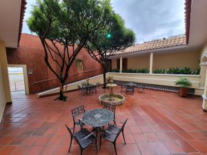 un patio al aire libre con mesas, sillas y árboles en Hotel Arizona Suites Cúcuta en Cúcuta