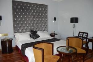 Staybridge Riverside Hotel & Spa في Broadhurst: غرفة نوم بسرير وطاولة وكراسي