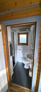 La salle de bains est pourvue de toilettes et d'un lavabo. dans l'établissement Kleiner Bungalow Am Wald, à Petershagen