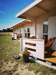 a white building with a porch with chairs and a table at Rio Park domki letniskowe Łukęcin in Łukęcin