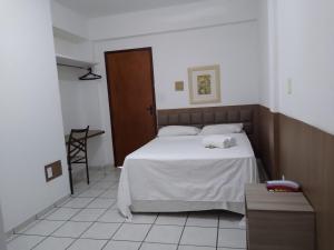a bedroom with a white bed and a table at One Hotel in João Pessoa