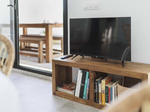 a flat screen tv on a wooden stand with books at Casa Ailanto in El Pozo de los Frailes