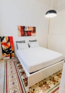 a white bed in a room with a rug at Daniel's Apartment in Bari