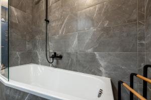a bath tub in a bathroom with a tile wall at Mojmirova Apartment Kosice Center in Košice