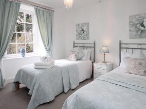 a white bedroom with two beds and a window at Dunster Mill House in Dunster