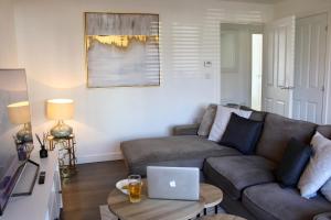 sala de estar con sofá y mesa con ordenador portátil. en Cicero Fairfields by Pay As U Stay en Milton Keynes