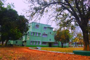un bâtiment vert avec un arbre en face dans l'établissement Jhargram Eshani Hotels and Guest House, à Jhārgrām