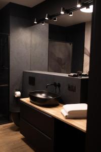 Baño negro con lavabo y espejo en Apartament No1 Wyszyńskiego, en Wroclaw