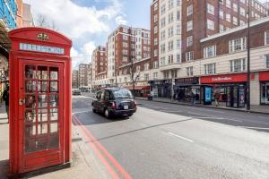 a red phone booth and a car on a city street at The Hyde Park Corner in London