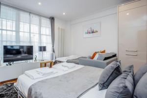 a white room with two beds and a television at The Hyde Park Corner in London