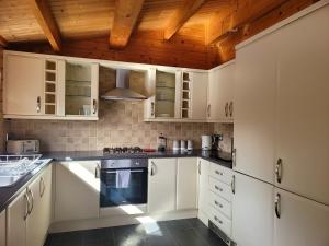 a kitchen with white cabinets and a wooden ceiling at Immaculate 2-Bed Lodge Next To Lake in Preston