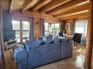 a living room with a blue couch and a television at Immaculate 2-Bed Lodge Next To Lake in Preston
