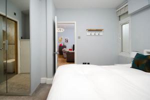 um quarto com uma grande cama branca e uma casa de banho em Charming Ground Floor 1 Bedroom Flat in Twickenham em Twickenham