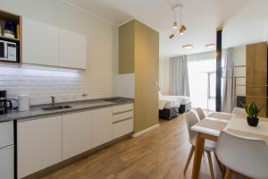 a kitchen with white cabinets and a table and a bedroom at Criollos Apartamentos in Ushuaia