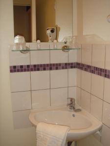 
a white sink sitting under a mirror in a bathroom at Au Royal Hotel in Carcassonne
