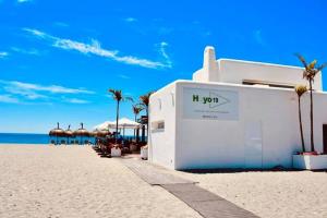 - un bâtiment blanc sur la plage avec des palmiers et l'océan dans l'établissement Apartamento Aguacate beach playa Granada, à Motril