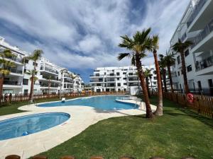 - une piscine bordée de palmiers et de bâtiments dans l'établissement Apartamento Aguacate beach playa Granada, à Motril