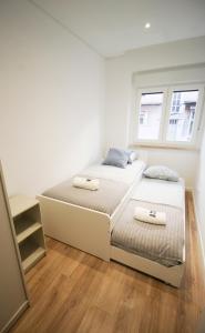 een witte slaapkamer met 2 bedden en 2 ramen bij Oriente DNA Studios X in Lissabon