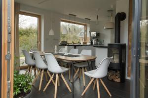 uma cozinha com uma mesa de madeira e cadeiras brancas em Ferienhaus Schleiharmonie em Ulsnis