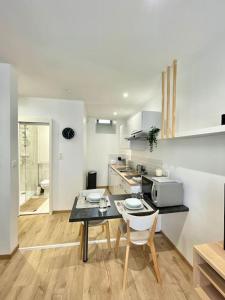 Biała kuchnia ze stołem i kuchenką mikrofalową w obiekcie Hyper centre appartement Cosy WIFI w mieście Rodez