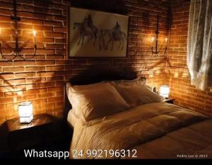 a bedroom with a brick wall and a bed with two lights at Pousada Romântica Serra da Mata in Penedo