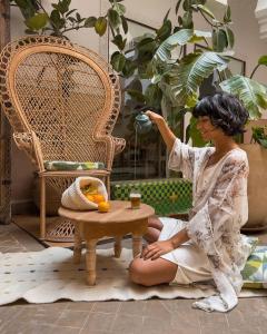 uma mulher sentada no chão ao lado de uma mesa em Monriad em Marrakech