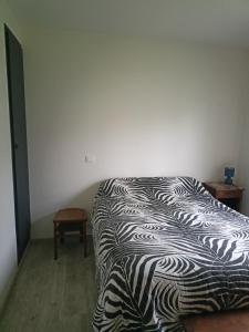 ein Schlafzimmer mit einer schwarzen und weißen Bettdecke auf einem Bett in der Unterkunft Brigitte Carbonnel in Aydat