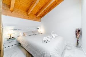 uma cama branca num quarto com tectos em madeira em Ático Santa Clara em Burgos
