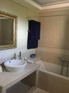 bagno con lavandino, vasca e specchio di Eva's cottage Kastelli Pediados a Kardhoulianós