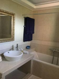 ein Badezimmer mit Waschbecken, Badewanne und Spiegel in der Unterkunft Eva's cottage Kastelli Pediados in Kardhoulianós