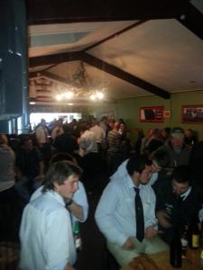 a group of men standing in a crowd in a room at Gladstone Hotel in Fairlie