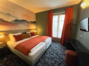 a bedroom with a bed with orange curtains and a tv at Montparnasse Daguerre in Paris