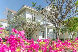 una casa blanca con flores rosas delante en Casa Villa - Ocean View - Sealinks City Resort en Phan Thiet