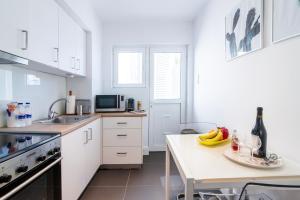 a kitchen with white cabinets and a table with bananas on it at Sun & Sea Suite, Kavouri in Athens