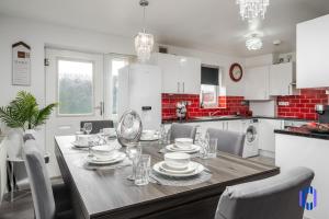 una cocina con una mesa con platos y vasos. en Spacious 5 BR Home Nr Etihad Stadium with Pool Table, en Mánchester