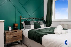 1 dormitorio con 2 camas y pared verde en Spacious 5 BR Home Nr Etihad Stadium with Pool Table, en Mánchester