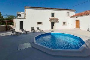 a swimming pool in front of a white house at Villa Rosa Kringa in Tinjan
