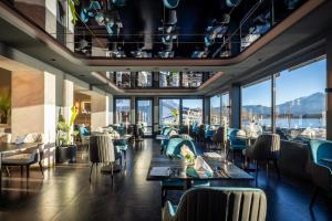a restaurant with tables and chairs and large windows at Hotel am Hopfensee in Füssen